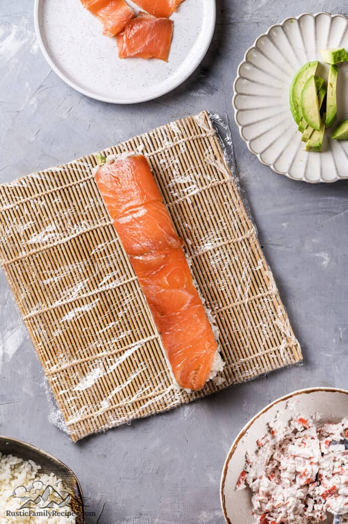 Adding salmon to the sushi roll