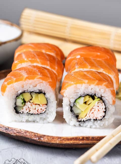 Slices of Alaska Roll on a plate with a mat behind