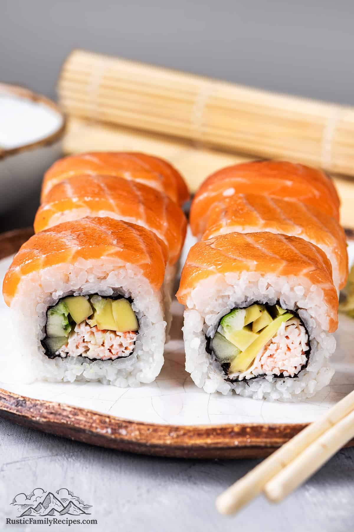 Slices of Alaska Roll on a plate with a mat behind