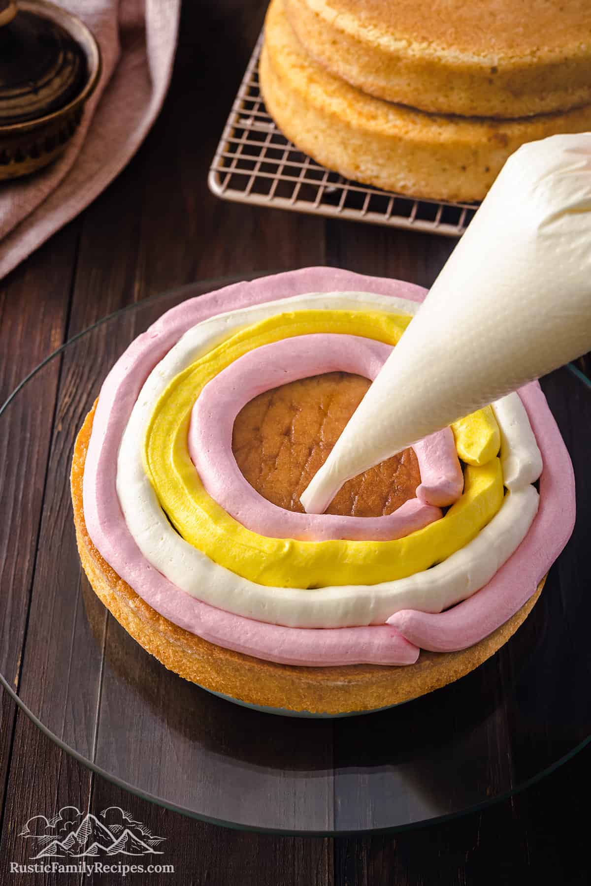Piping white, pink and yellow frosting in between cake layers