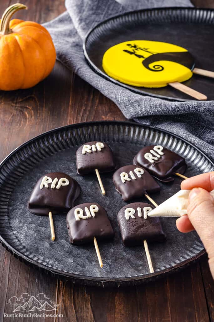 Graveyard cookies coated in chocolate with RIP written in white buttercream.