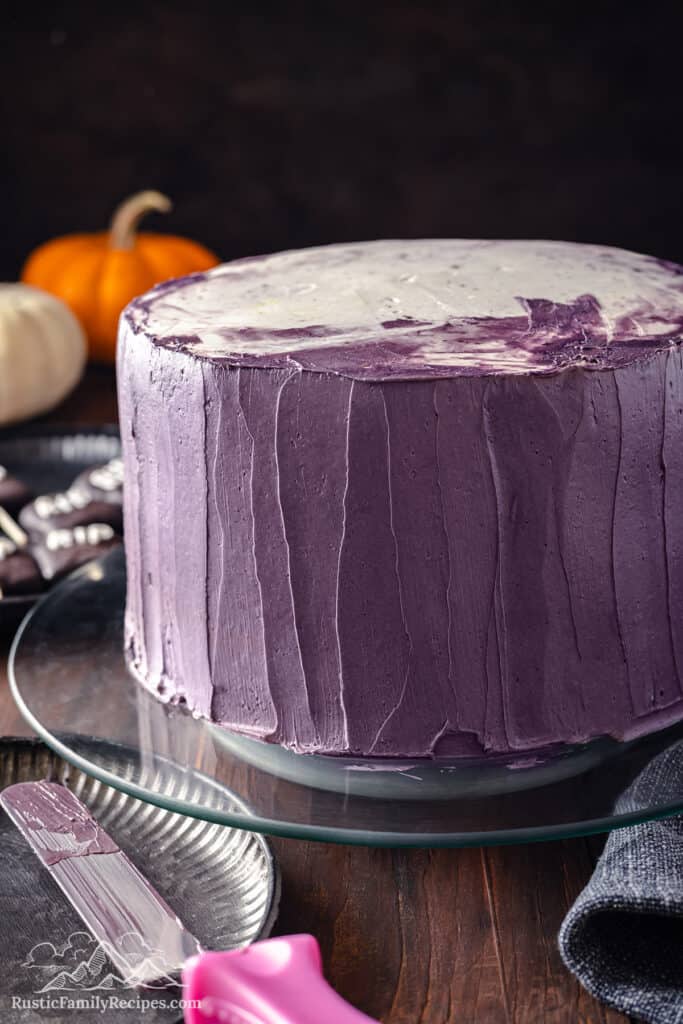 Purple buttercream frosted cake on a glass platter.