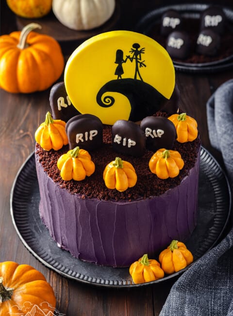 Nightmare Before Christmas cake decorated with a Spiral Hill yellow sugar paste topper, buttercream pumpkins, and graveyard cookies.