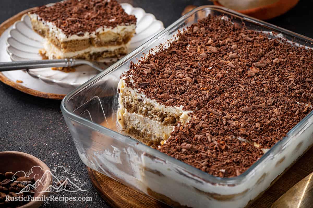 Classic tiramisu in a glass container with layers of ladyfingers and mascarpone cream, topped with bittersweet chocolate.