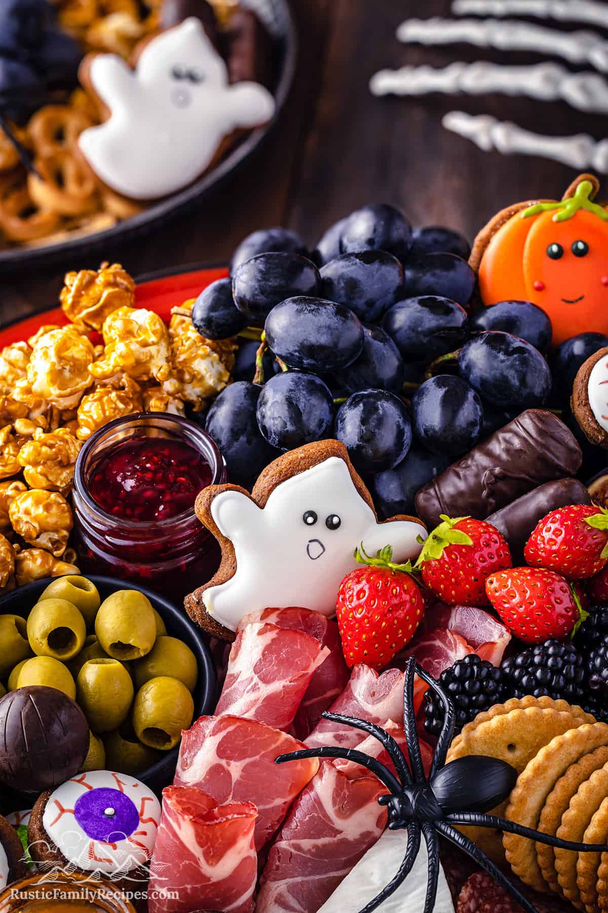 A halloween themed charcuterie board with a skeleton hand and ghost cookies