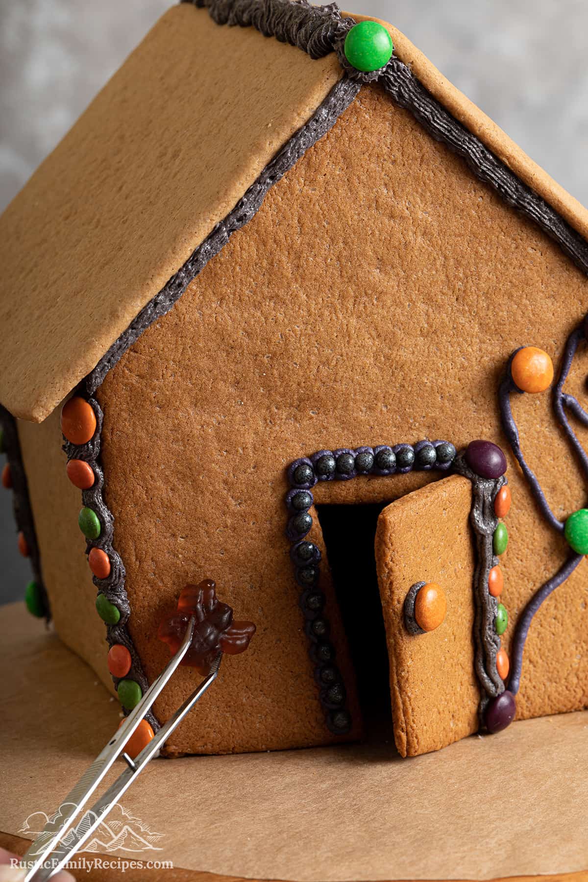 Adding gummy spiders to the gingerbread house.