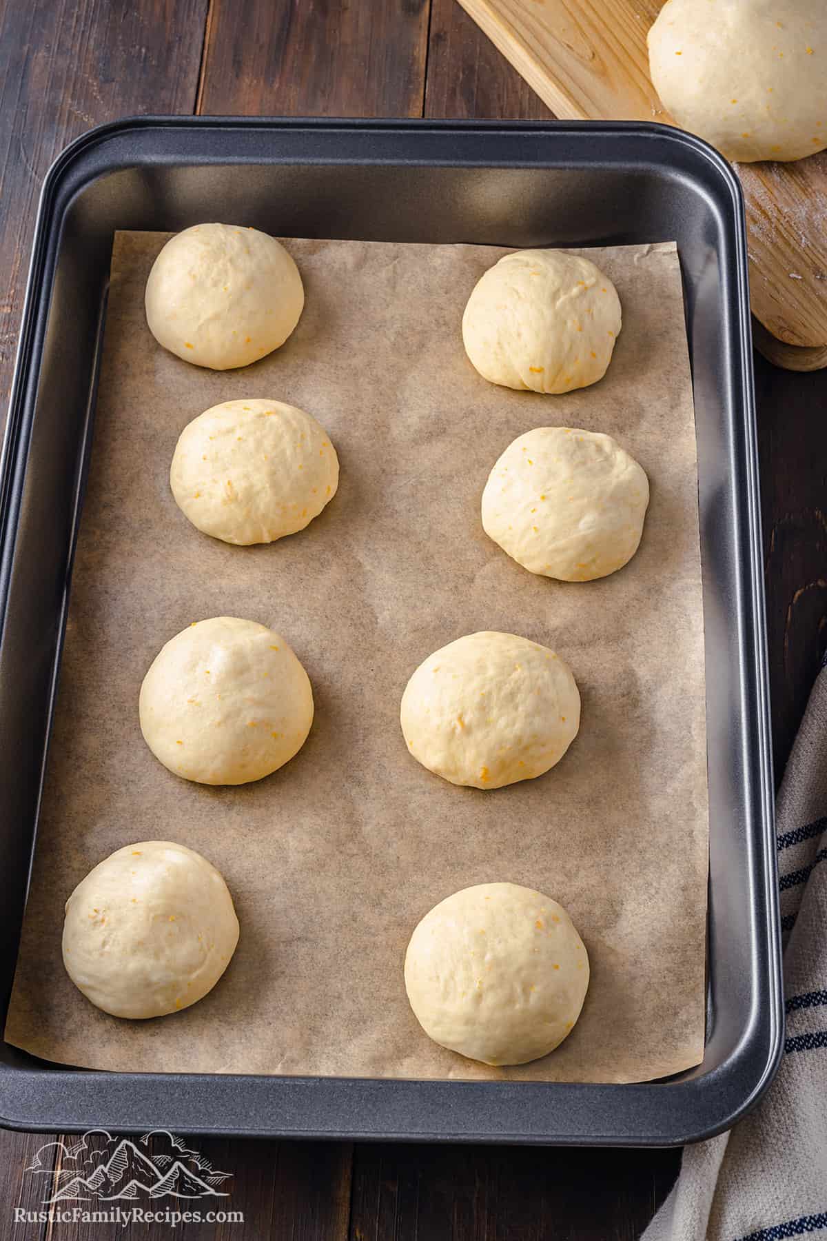 8 balls of dough for pan de muerto on a prepared baking tray.