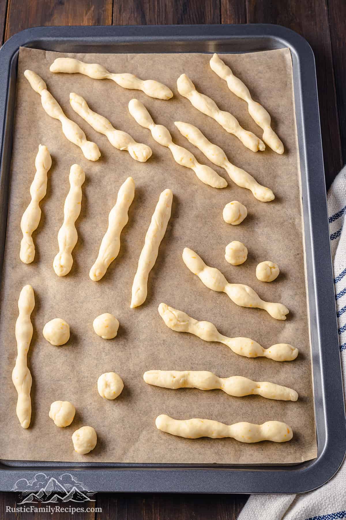 Shaped dough skulls and bones on a prepared baking tray.