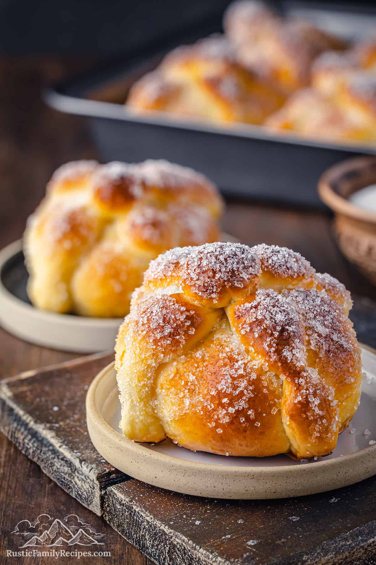 Pan de muerto sprinkled with sugar on a plate.