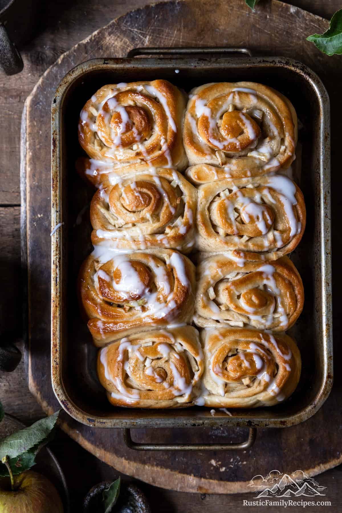 apple cinnamon buns in a baking dish with icing on top