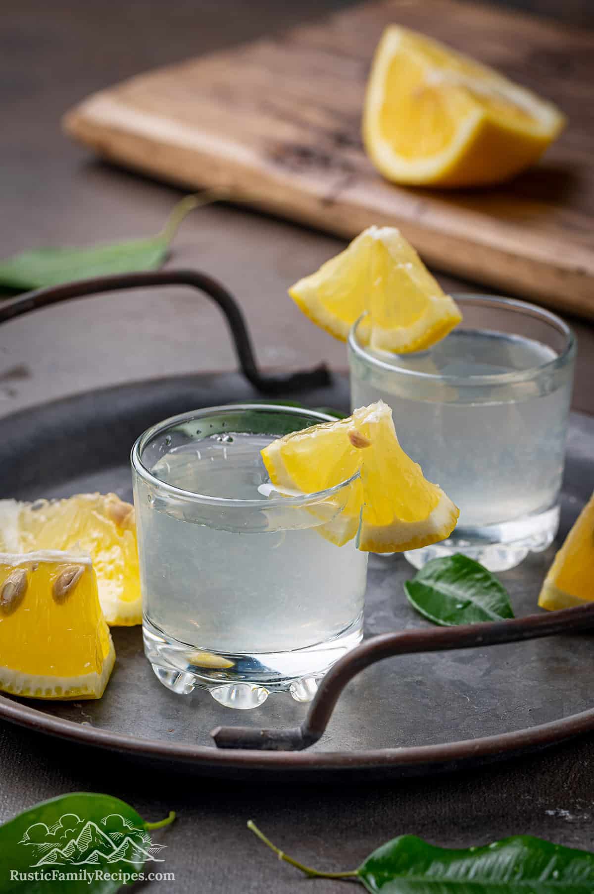 Two white tea shots with lemon wedges on a serving platter