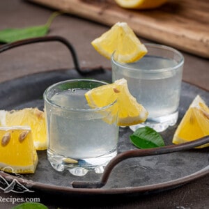 Two white tea shots with lemon wedges on a serving platter