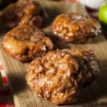 3 apple fritters on a wood cutting board