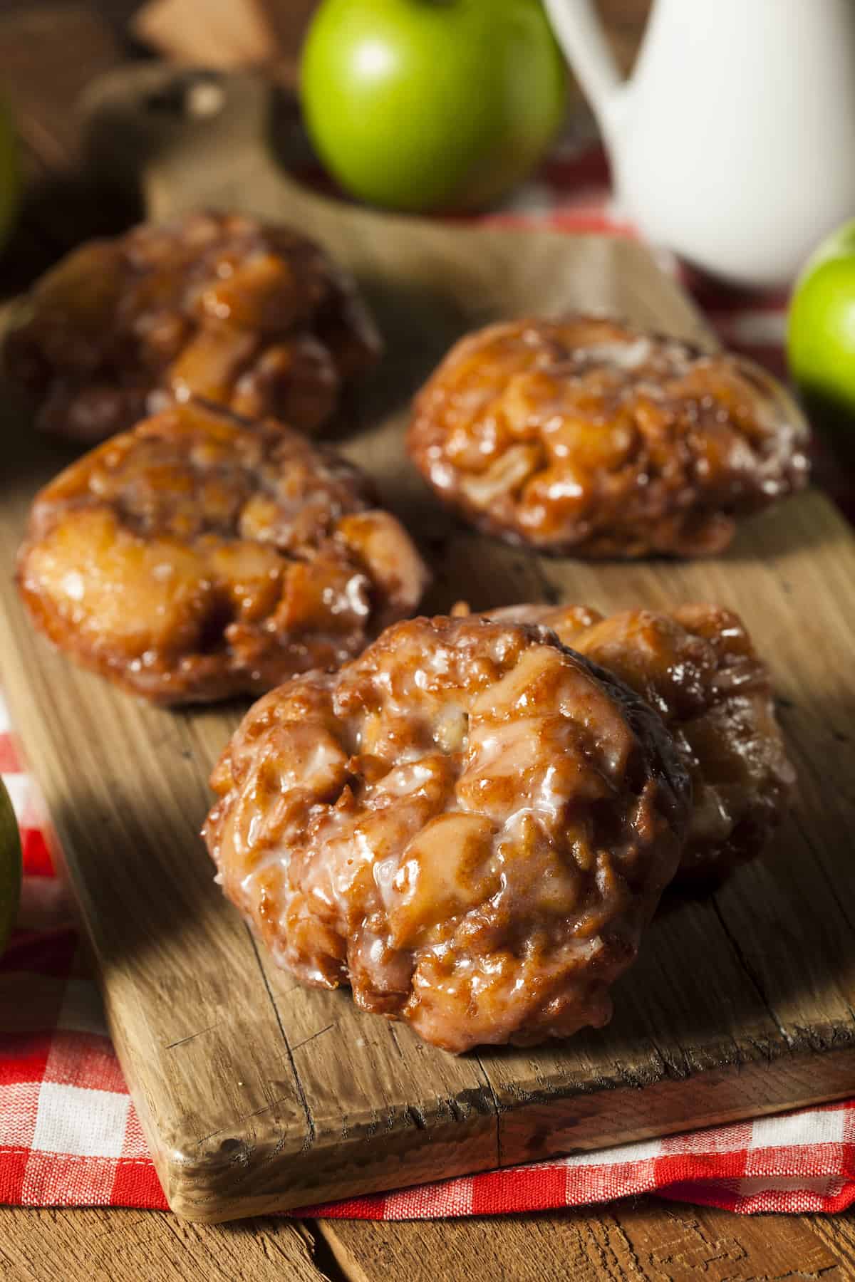 3 apple fritters on a wood cutting board