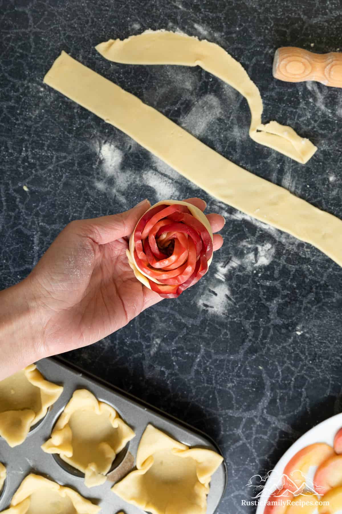Holding an unbaked Apple Rose Tartlet