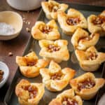 Apricot brie bites on a baking sheet next to salt and walnuts