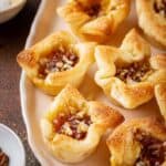 A tray of apricot brie bites next to salt and walnuts