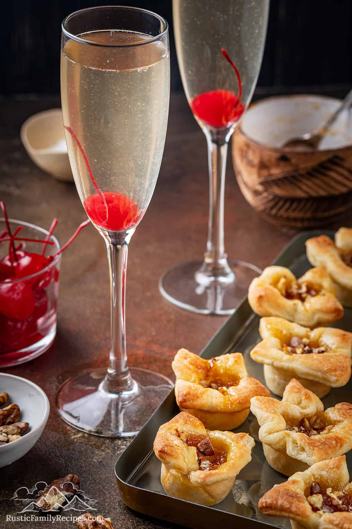 Two french 76 cocktails next to a tray of brie bites