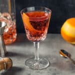 Negroni Sbagliato in a glass next to a jigger and an orange