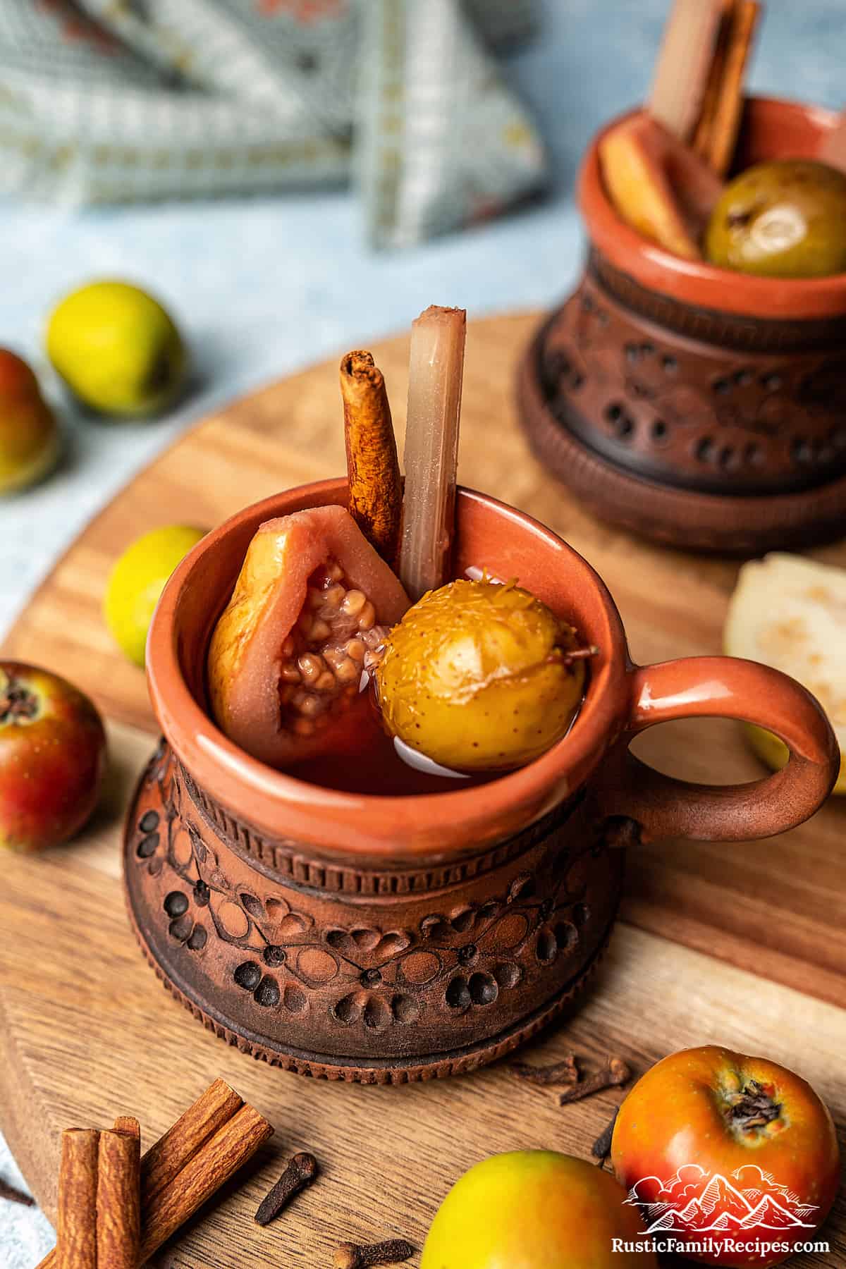 Ponche de frutas navideño in a cup with fruit and a cinnamon stick.