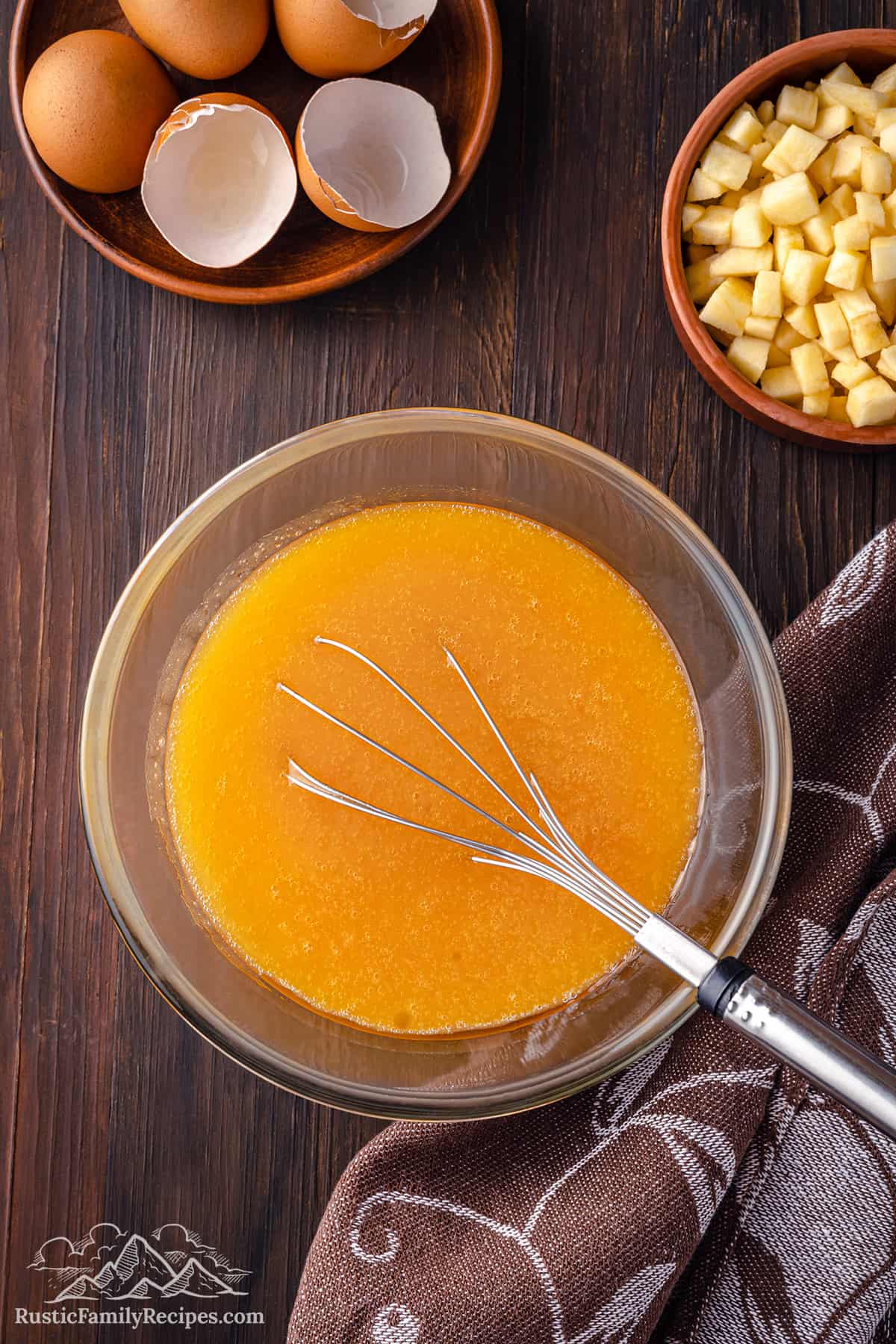Mixing wet ingredients for pumpkin muffins in a glass bowl with a whisk