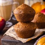 Two Pumpkin Apple Muffins stacked on top of each other next to pumpkin spice lattes