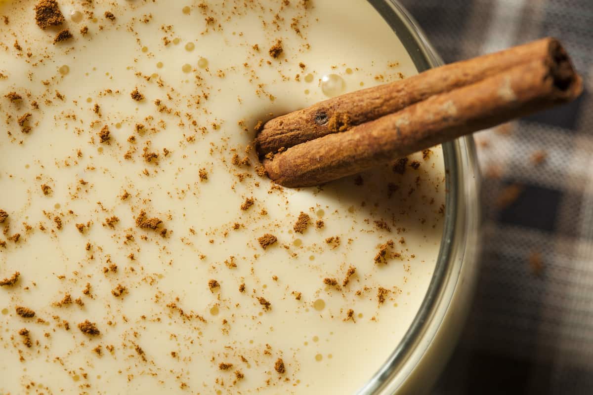 Close-up of rompope sprinkled with ground cinnamon and served with a cinnamon stick,