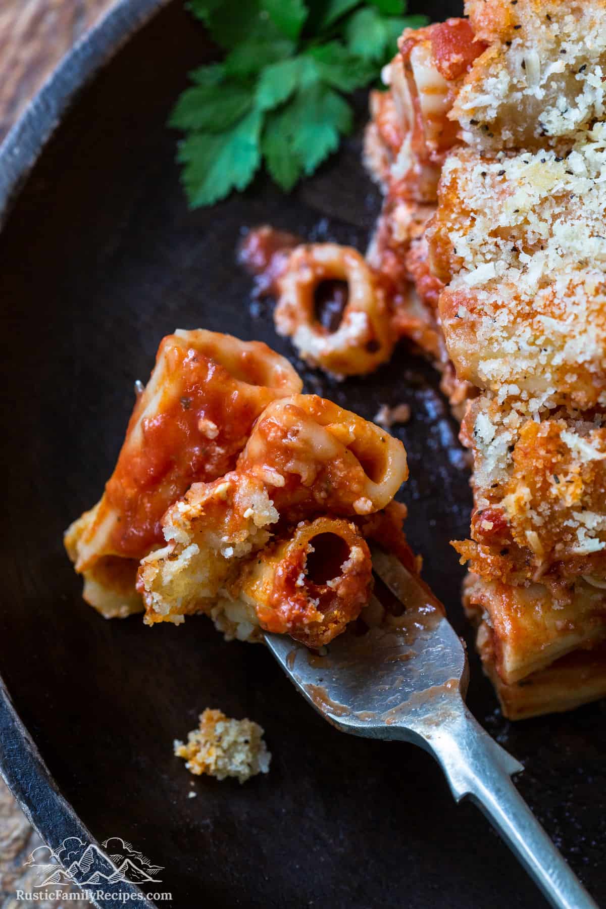A fork with a bite of ziti al forno on it
