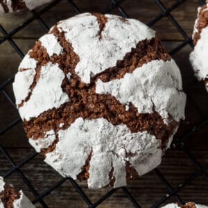 A chocolate crinkle cookie on a black cooling rack