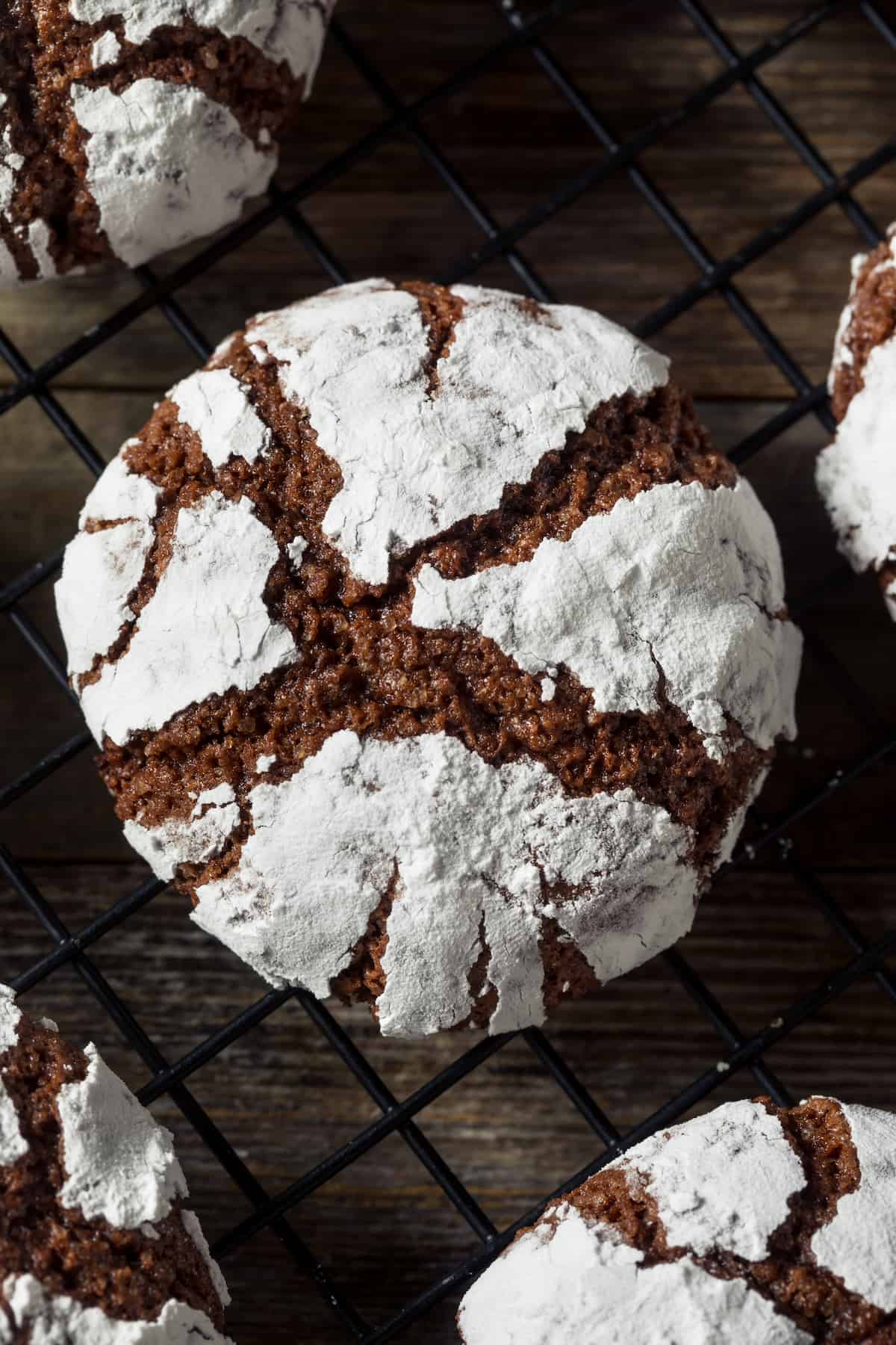 A chocolate crinkle cookie on a black cooling rack