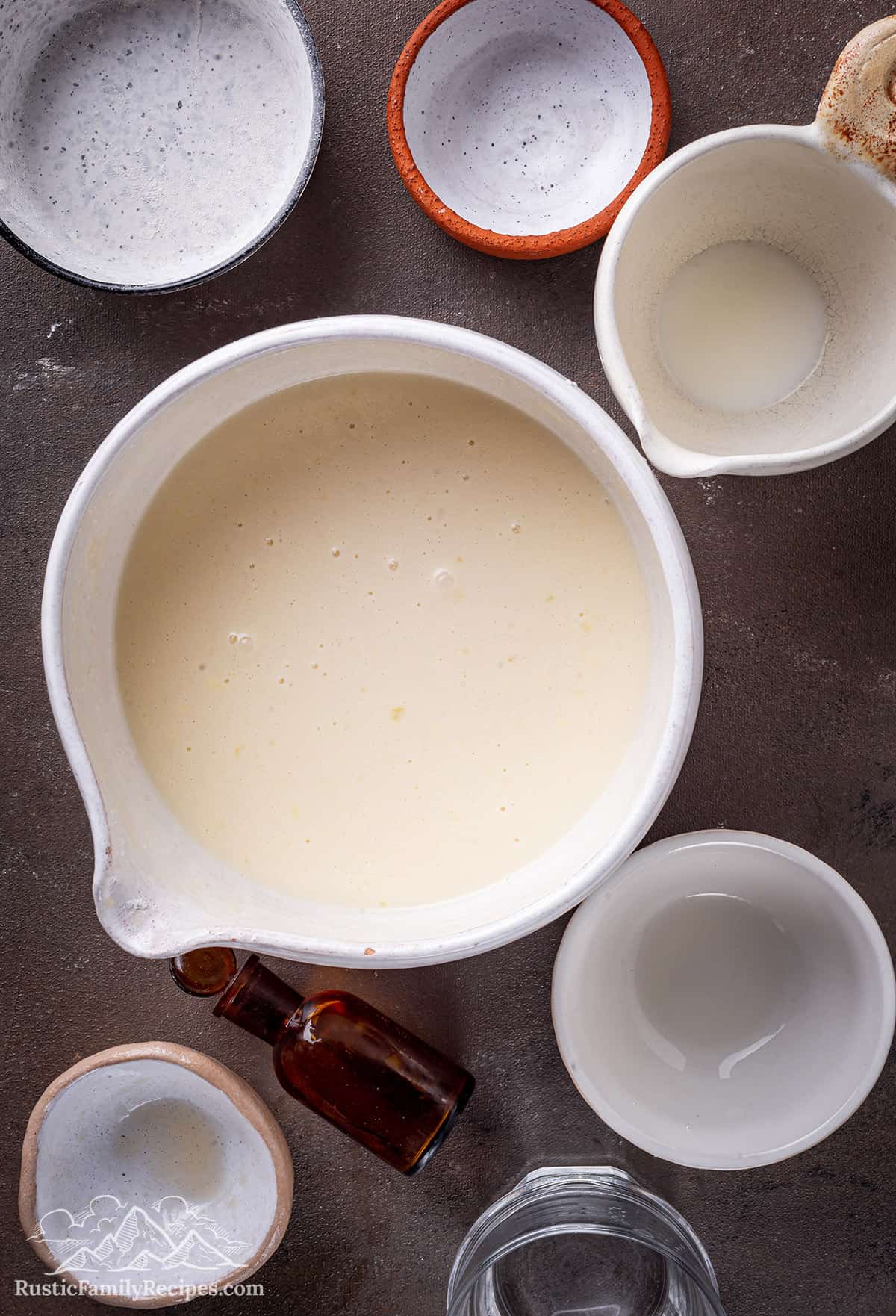 Crepe batter for Frumple Cakes in a white bowl next to empty bowls