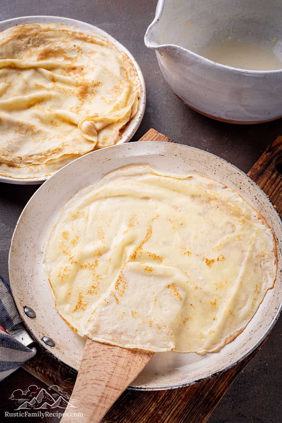 A plate of homemade crepes with a spatula lifting one