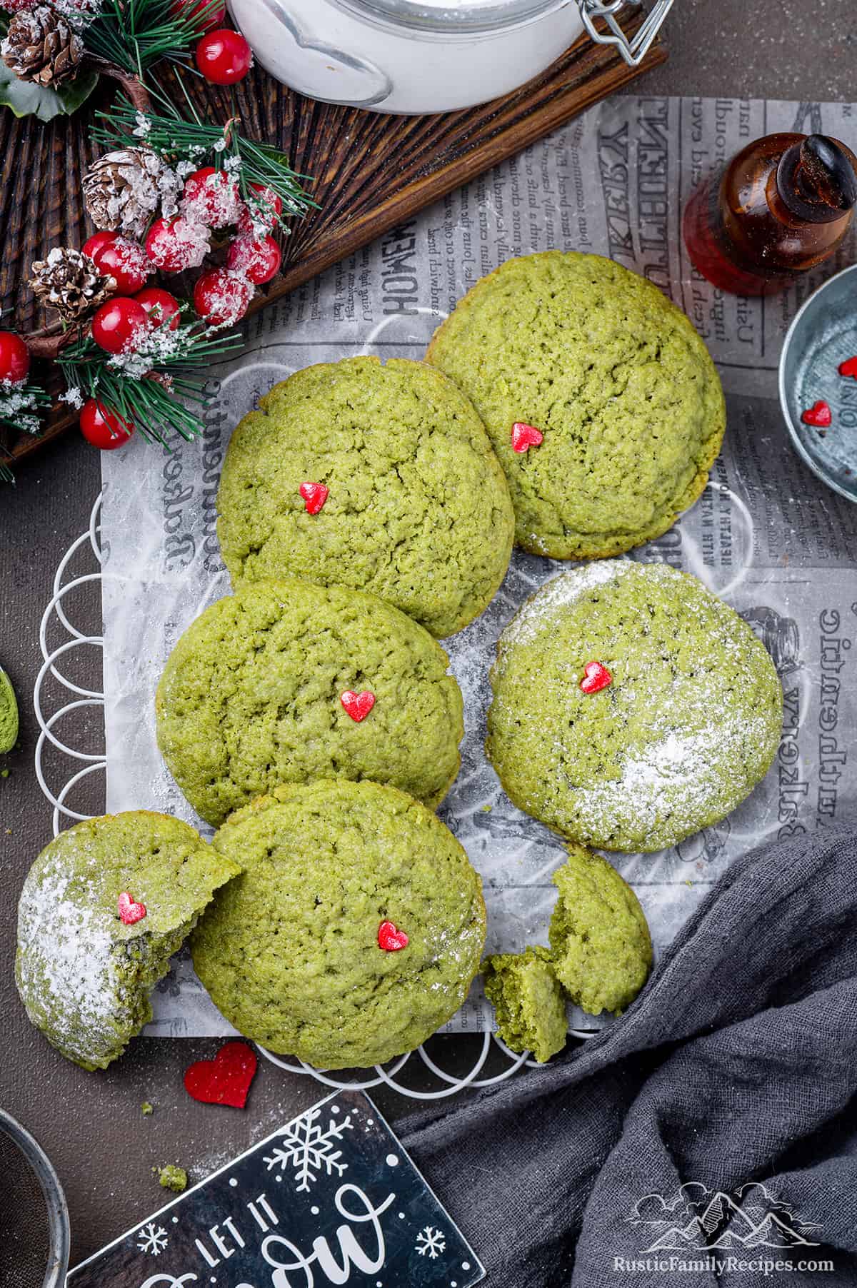 Green Grinch Cookies on parchment with festive decoration, sprinkled with confectioners sugar