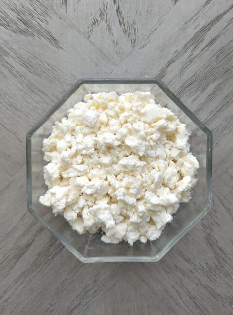 Overhead of cotija cheese in a glass bowl.
