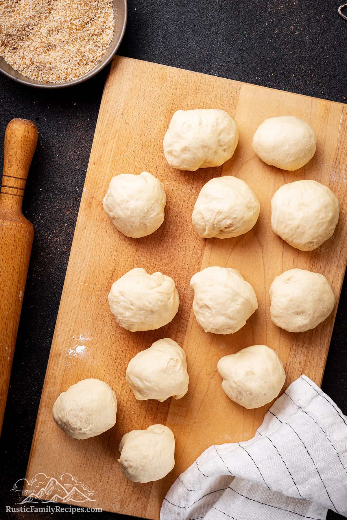 Balls of dough rising on a wood cutting board