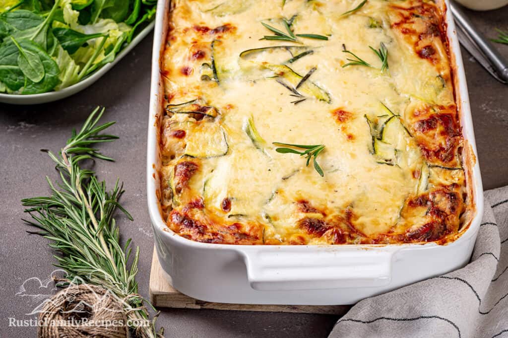 A white casserole dish with Roasted Chicken Bechamel Lasagna