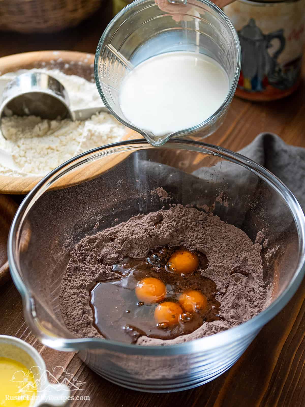 Adding eggs and milk to the dry ingredients in a glass bowl