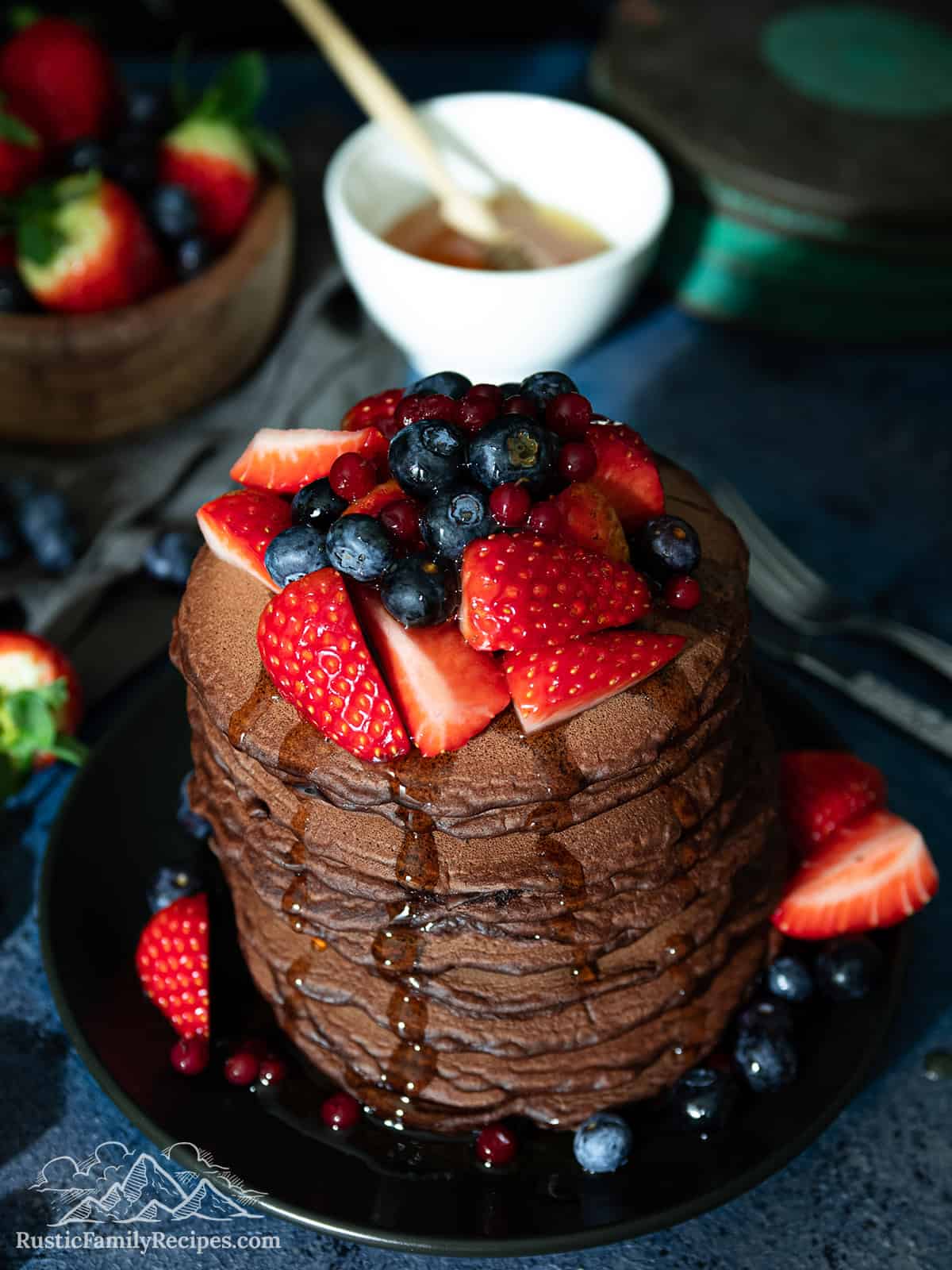 A stack of chocolate pancakes with syrup being poured on top