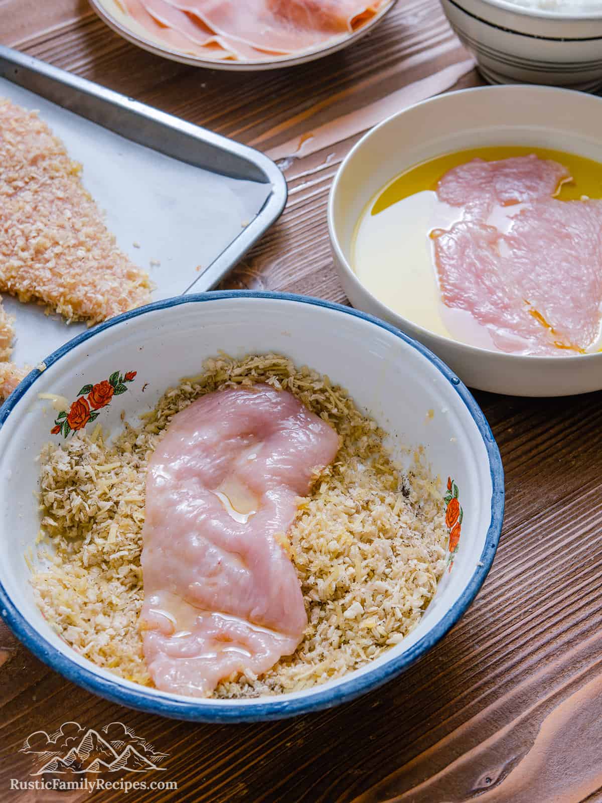 Breading sliced chicken breasts in a white bowl