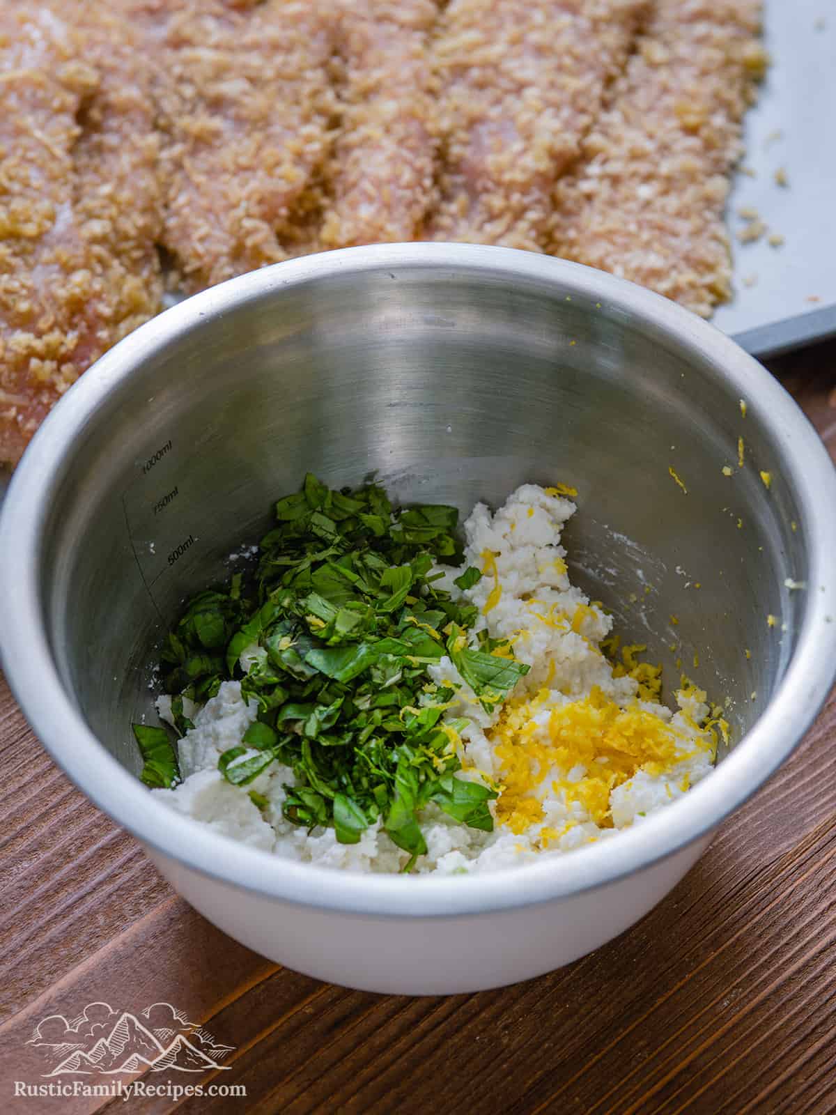 A steel bowl with ricotta and herbs for chicken rollatini