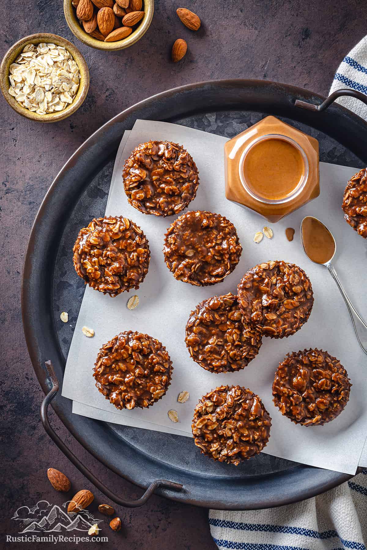 7 no bake chocolate oatmeal cookies on a plate next to almond butter and almonds