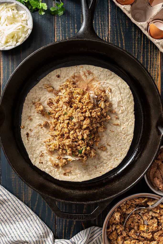 Adding the filling to a flour tortilla. 