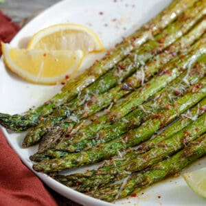 Roasted asparagus on a white plate with lemon