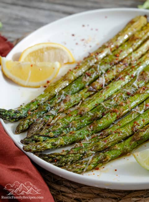 Roasted asparagus on a white plate with lemon