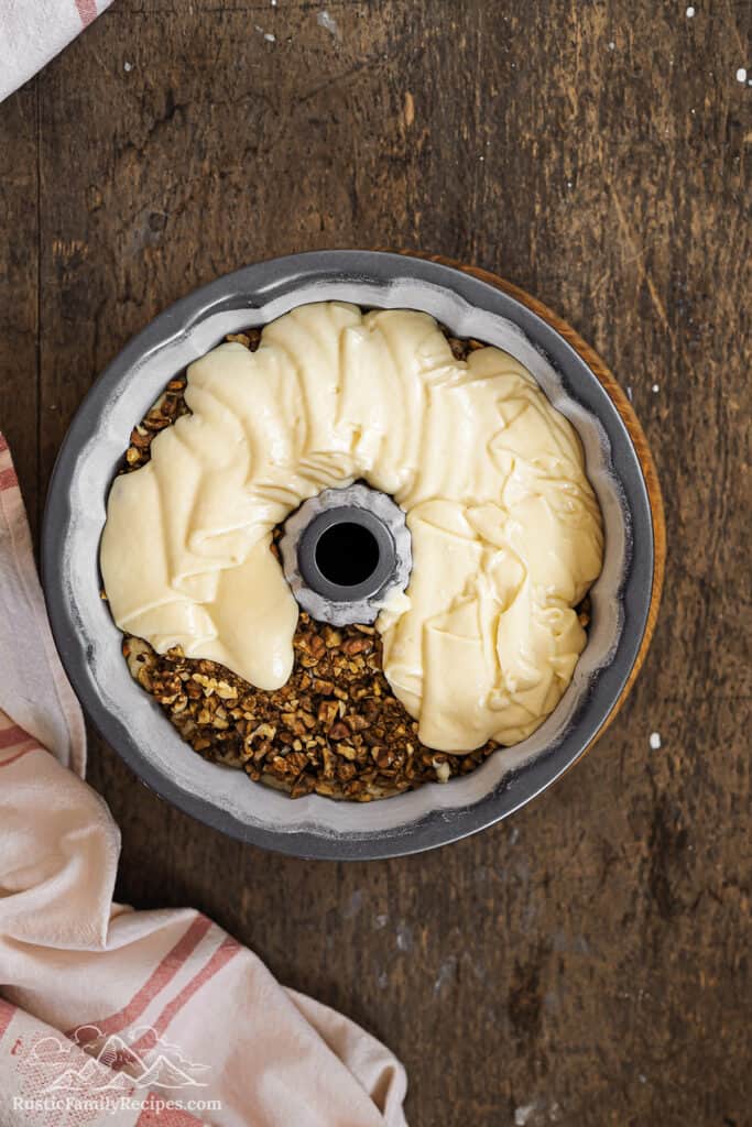 Adding cake batter to the bundt pan with the filling in it