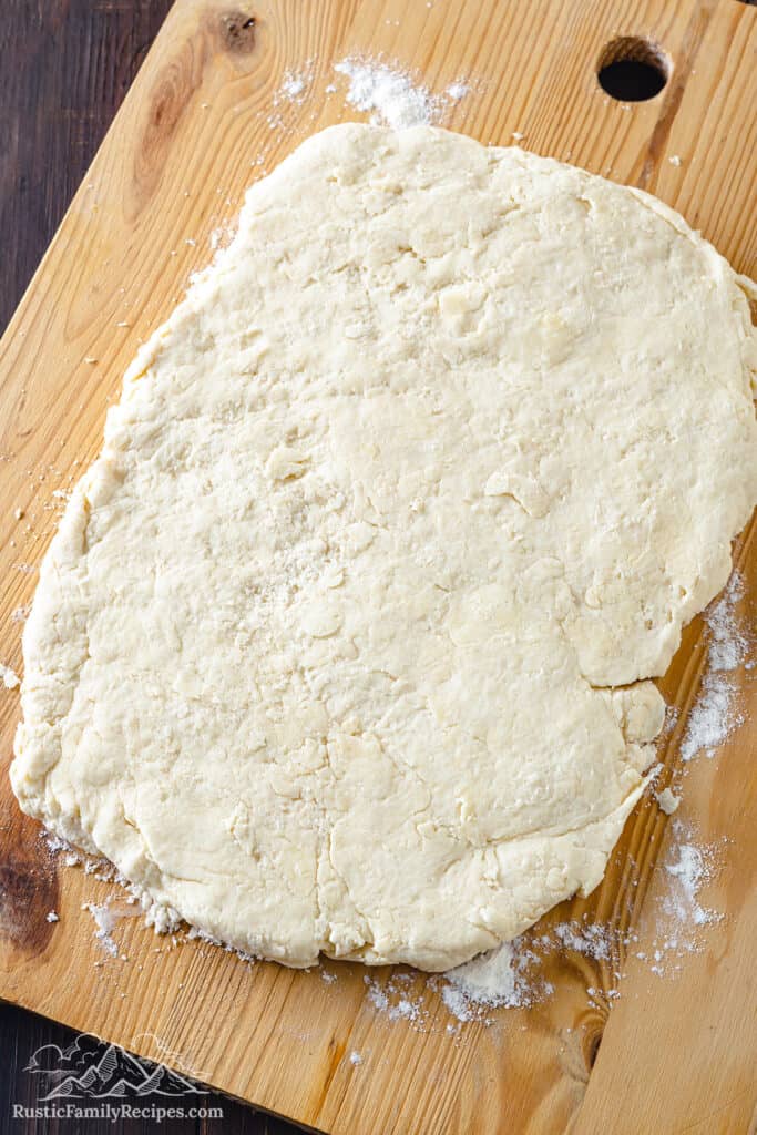 Rolling out biscuit dough on a floured work surface.
