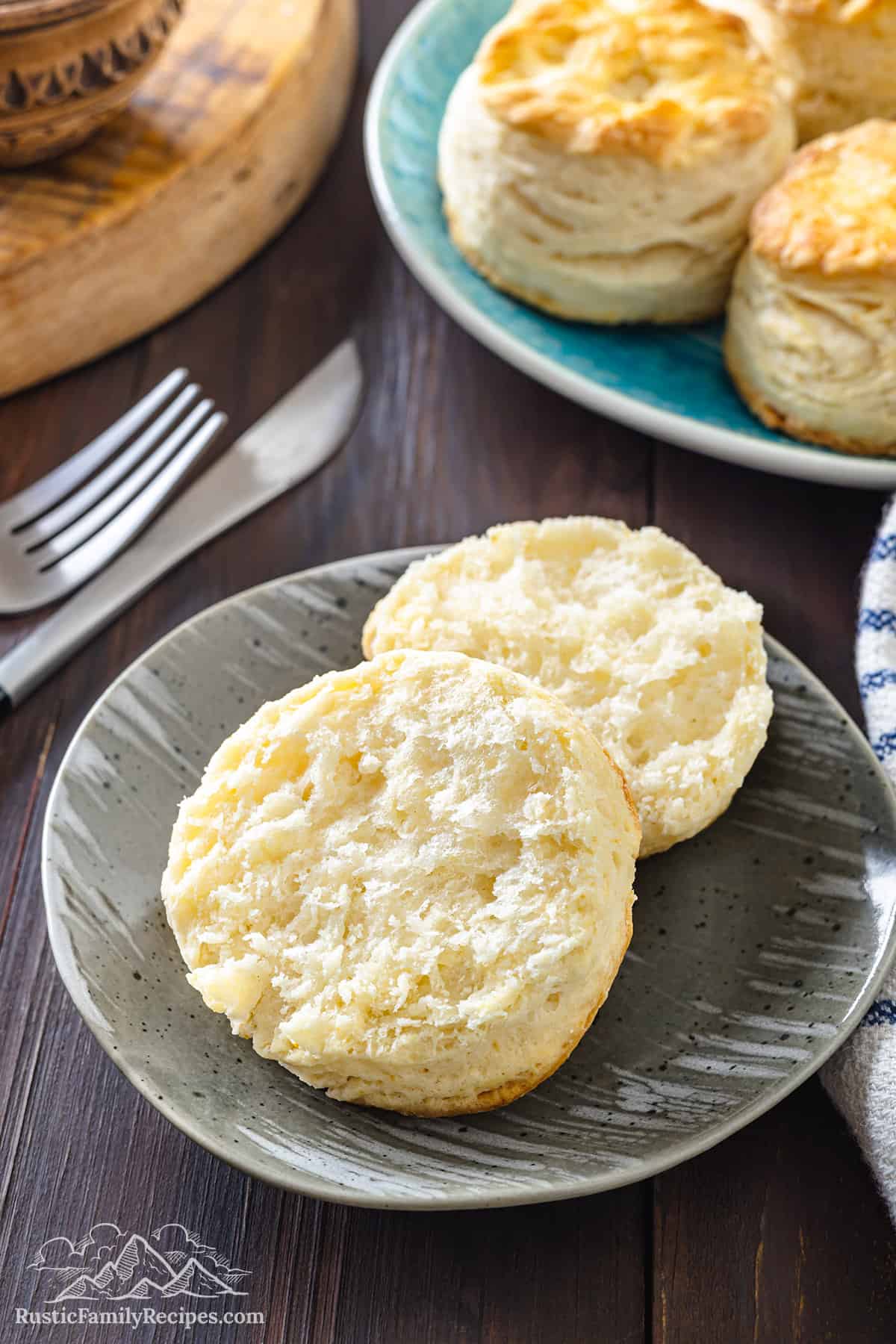 A cathead biscuit on a plate sliced in half.