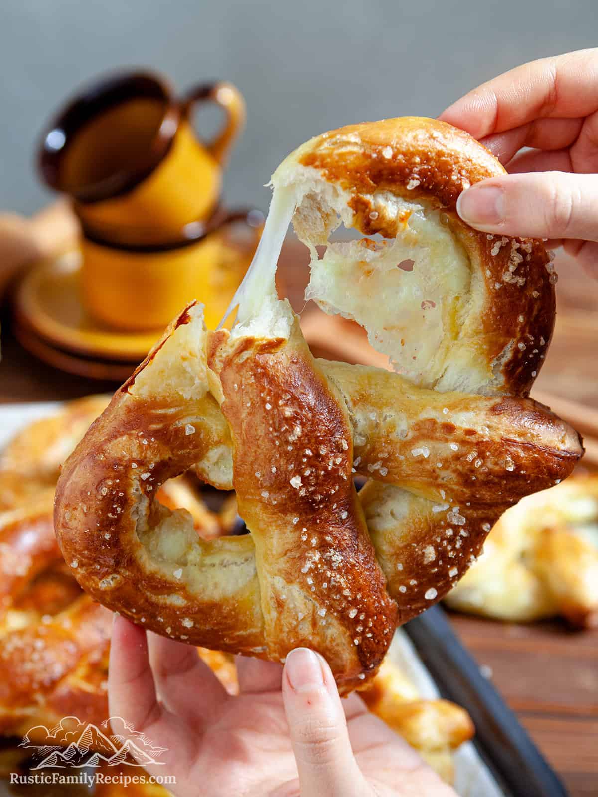 Hands breaking open a pretzel stuffed with cheese