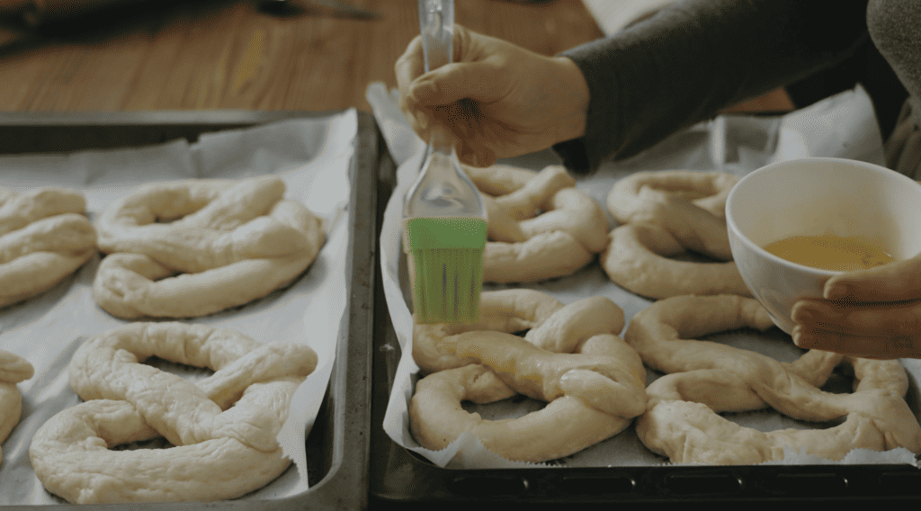 adding egg wash to pretzels that are ready to bake