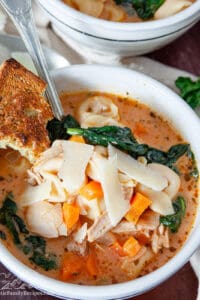 A white bowl filled with chicken tortellini soup.